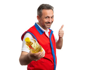 Supermarket employee making thumb up gesture to oil bottle.