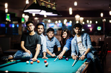 Group Of Stylish Asian Friends Wear On Jeans Playing Pool Billiard On Bar.