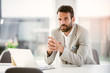 © JustLife - Businessman sitting looking at his laptop. Businessman working in the office on his laptop. Stylish businessman working on a project in the office thinking about future
