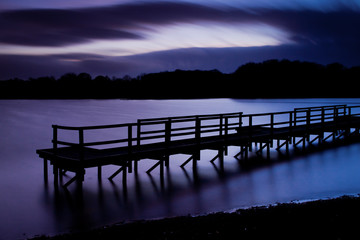 An abstract shot of a jetty over the water with a dramatic sunset in the background