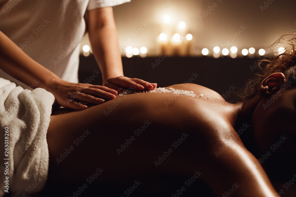 African-american woman enjoying salt scrub massage at spa - obrazy, fototapety, plakaty 