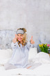 beautiful blond and young woman, wearing sleeping mask, sitting in bed and doing yoga exercises in the morning