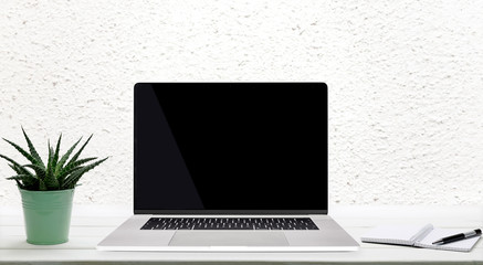 Wall Mural - moder worplace concept - generic silver laptop with a blank screen on a wooden table in the room.