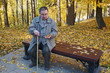© YuSafa - an elderly man on a bench in a city park, on his hand an autumn maple leaf
