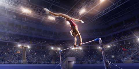 Wall Mural - Female athlete doing a complicated exciting trick on horizontal gymnastics bars in a professional gym. Girl perform stunt in bright sports clothes