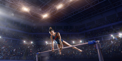 Wall Mural - Female athlete doing a complicated exciting trick on horizontal gymnastics bars in a professional gym. Girl perform stunt in bright sports clothes