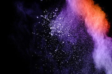 Wall Mural - purple orange color powder explosion cloud on black background.closeup of purple orange dust particl