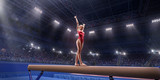 Female athlete doing a complicated exciting trick on gymnastics balance beam in a professional gym. Girl perform stunt in bright sports clothes