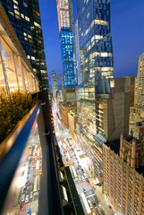 Amazing skyscrapers in Midtown Manhattan, aerial view from rooftop with traffic reflections on the buildings at night