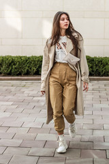 Wall Mural - Portrait shooting of a stylish girl. Beige shades. Trends of spring and summer 2019. Pants of cork.Trench cloak, a wide jacket.