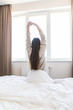 © F8  \ Suport Ukraine - Young woman stretching in the bed after wake up in the morning