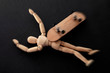 Dangerous injury, risky behavior and extreme sports concept theme with a wooden puppet and a skateboard make of wood falling to the ground and getting injured isolated on black background