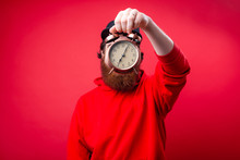 Handsome Guy In Red Hoody  Covering His Head With Vintage Clock Over Red Isolated Background