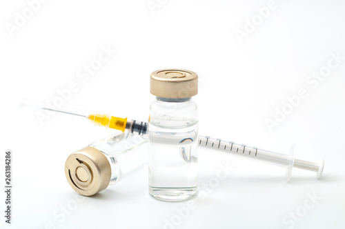 Vaccines, botulinum toxin and insulin ampules concept theme with glass vials with clear liquid next to a syringe and a hypodermic needle isolated on white background