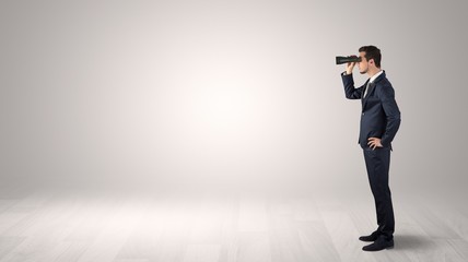 Wall Mural - businessman looking forward with binoculars in an empty space