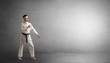 © ra2 studio - Small karate man fighting in an empty grey copy space
