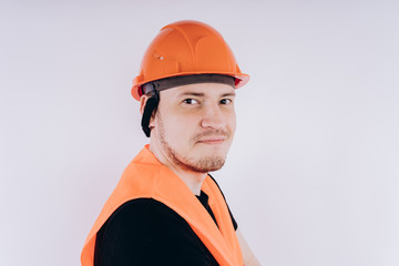 Man in working uniform on white background Portrait of young male in bright orange protective hardhat and vest looking at camera on white background