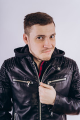 Wall Mural - Man in trendy jacket on white background Portrait of young male in leather jacket zipping up and smiling at camera on white background