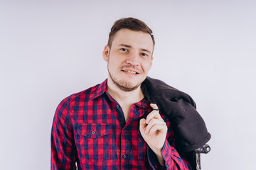 Wall Mural - Cool man with jacket on shoulder Portrait of young handsome male in red plaid shirt holding leather jacket on shoulder against white background