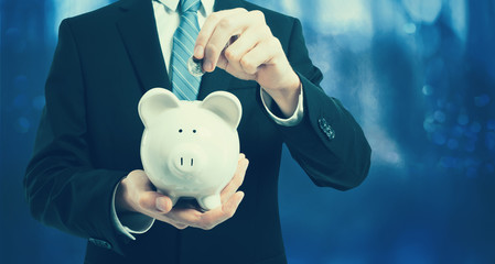 Businessman holding a piggy bank on a dark blue background