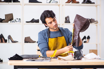 Young man repairing shoes in workshop 