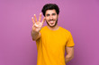 © luismolinero - Handsome over isolated purple wall happy and counting four with fingers