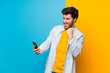 © luismolinero - Handsome over isolated colorful background with phone in victory position