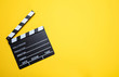 Movie clapperboard on yellow color background, top view