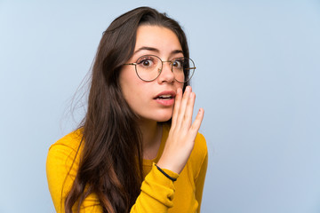 Wall Mural - Teenager girl over isolated blue wall whispering something