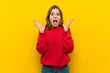 © luismolinero - Young woman over yellow wall with shocked facial expression