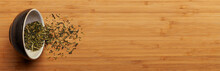 Spilled Japanese Kukicha Green Tea From Cup Over Bamboo Board