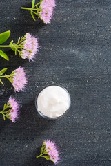 Sticker - moisturizer with pink flowers on old black wood table