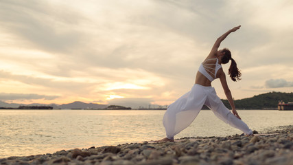 Wall Mural - Rear view of woman doing exercise yoga. standing in Warrior lI pose. Amazing yoga landscape in beautiful sky and enjoying sea view with morning, concept for exercising, health care,copy space for text