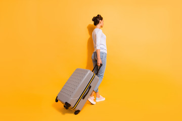 Wall Mural - Full length back rear behind body size photo beautiful hairdo she her lady go registration flight documents airport service wear casual jeans denim pullover big trolley isolated yellow background