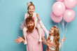 © WHstudio Leushin N - Two funny naughty sisters play together, tickle each other being cared by dad. Cute little girl holds bunch of air balloons. Happy family of father and two daughters prepare for holiday, pose indoor