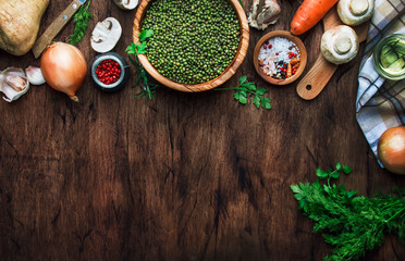 Wall Mural - Food cooking background. Ingredients for prepare green lentils with vegetables, spices and herbs, wooden kitchen table background, place for text. 