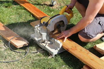 Wall Mural - A worker saw wood with a chop saw