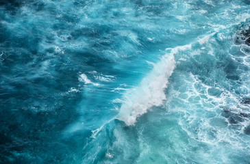 Wall Mural - waves and azure water as a background. view from high rock at the ocean surface. natural summer seas