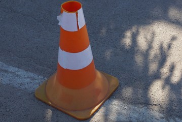 striped plastic cone stands on the gray asphalt road