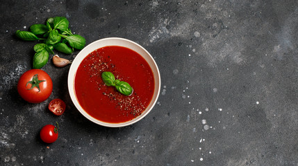 Traditional Spanish cold tomato soup gazpacho in a white bowl on a dark stone background. Traditional Spanish food. Concept of Spanish cold soup made of ripe tomatoes. Copy space, top view soup.