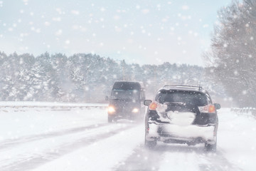 Wall Mural - Winter, snow, Blizzard, poor visibility on the road. Car during a Blizzard on the road with the headlights.