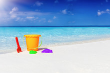 Family Vacation Concept: Colorful Toys On A Tropical Beach With Turquoise Sea And Sunshine
