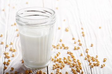 Poster - Non-dairy alternative Soy milk or yogurt in mason jar on white wooden table with soybeans aside