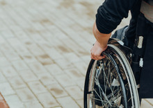 Close-up Of Male Hand On Wheel Of Wheelchair During Walk In Park