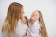 © goldeneden - real family of caucasian mother and daughter in white shirts in the studio background