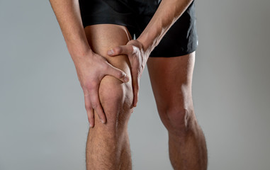 Sport man injured when exercising or running holding his knee in pain