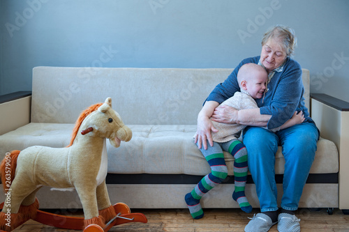 Elderly Woman Sits And Plays With Her Grandson On Couch Child Is