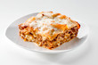 freshly baked lasagna piece on white plate close-up 