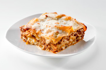 freshly baked lasagna piece on white plate close-up 