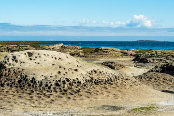 beautiful sandstone beach on a sunny day with blue ocean and cloud in the background